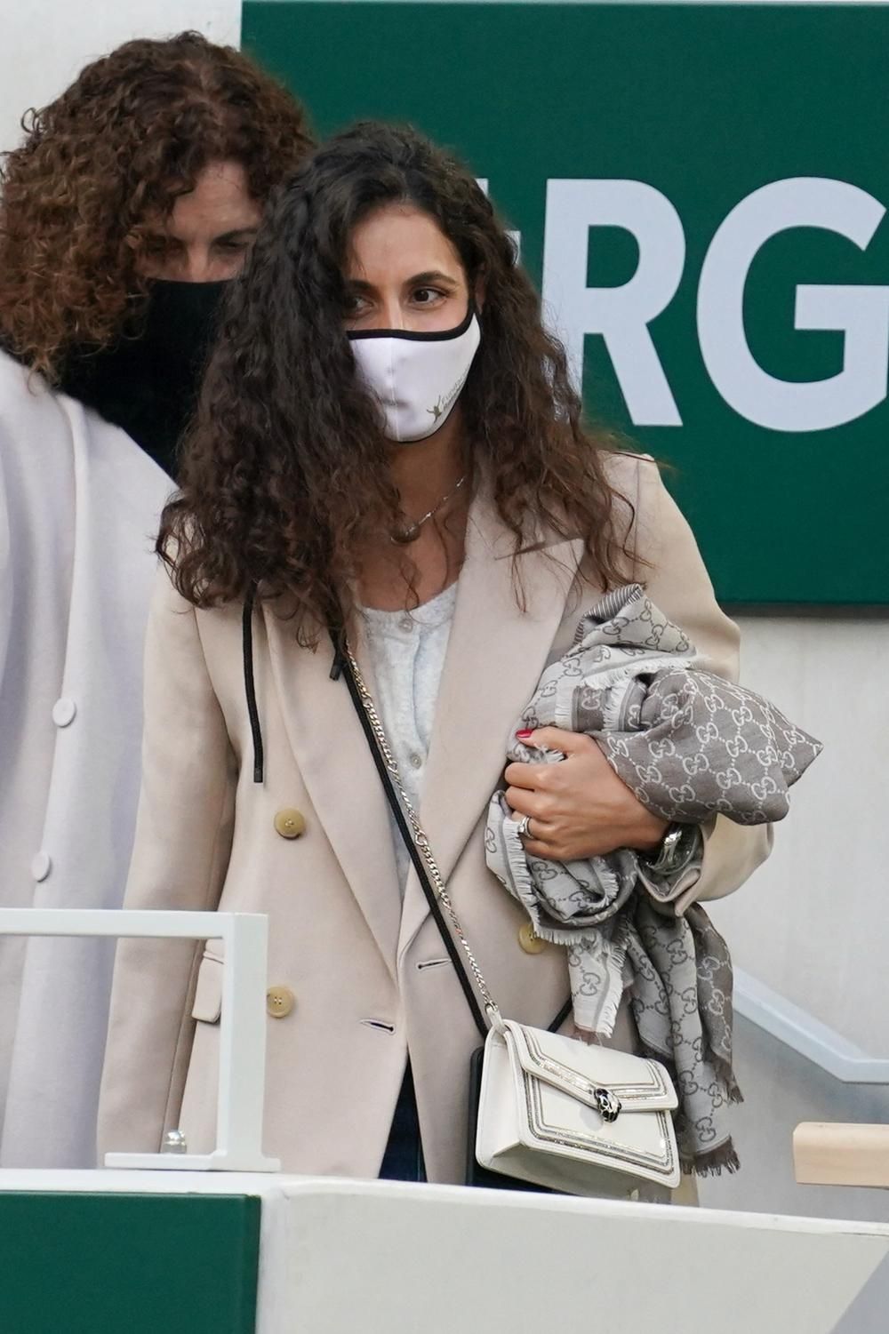 Mery Perelló en la pista central de Roland Garros con abrigo cruzado, rebeca gris, vaqueros y bolso blanco cruzado