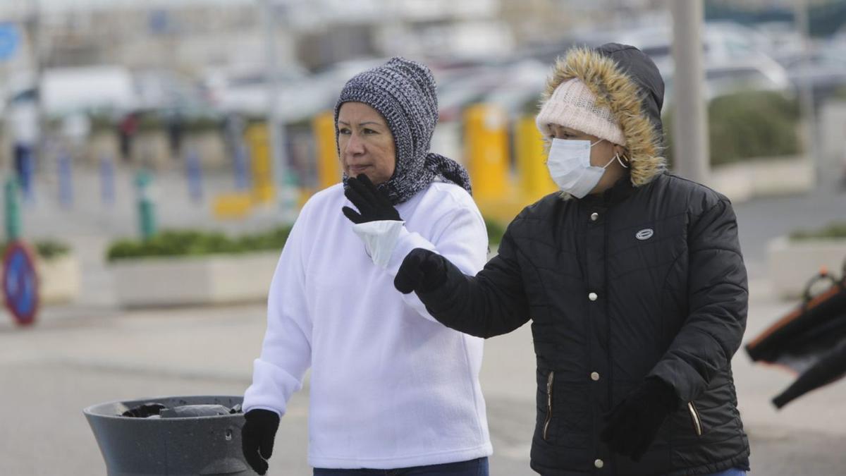 Dos mujeres pasean por la playa en València, muy abrigadas. | EDUARDO RIPOLL