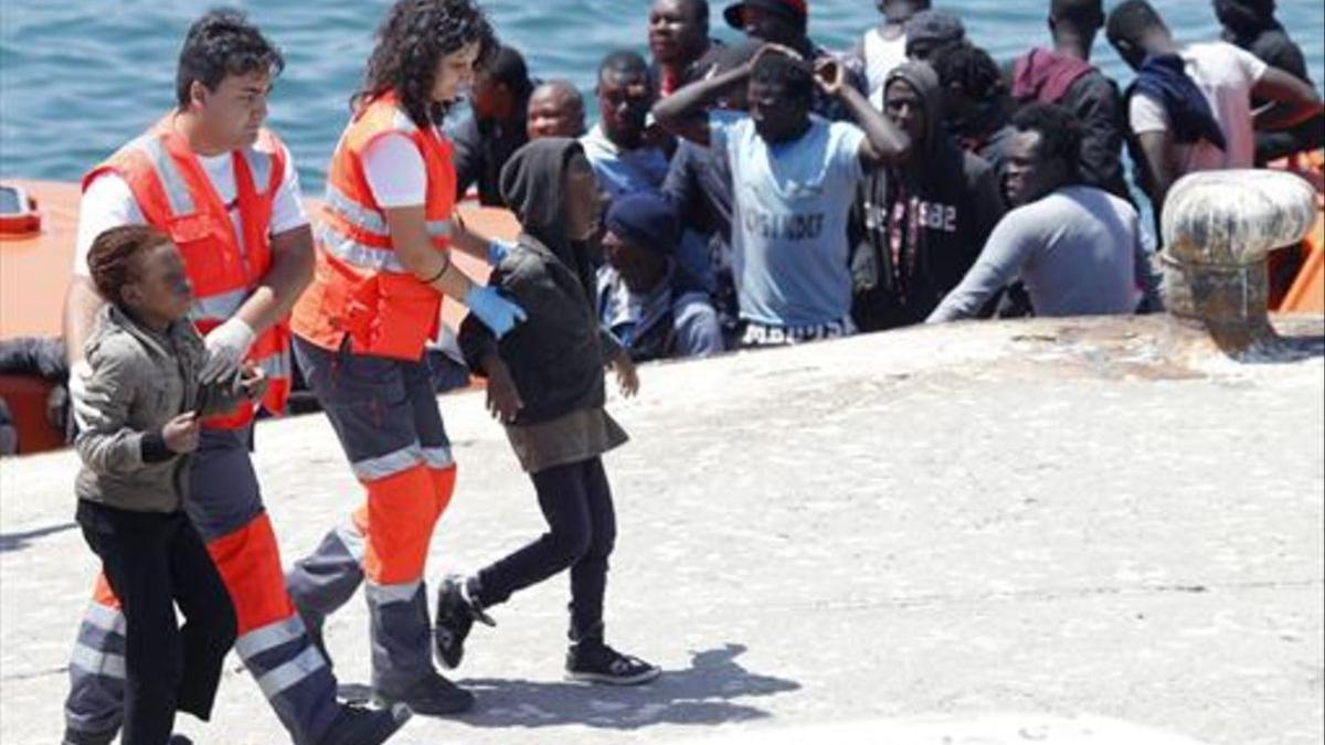 Miembros de la Cruz Roja acompañan a unos menores inmigrantes a su llegada al puerto de Tarifa.