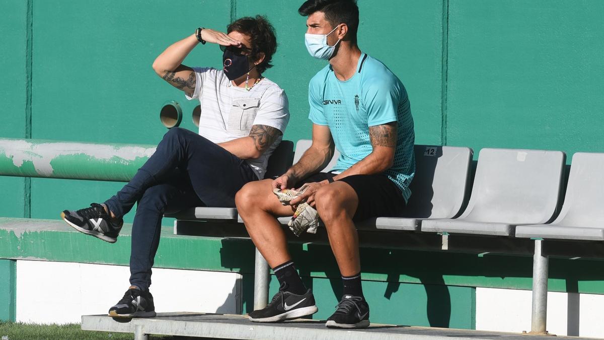 Willy (d) observa el entrenamiento de sus compañeros junto a Raúl Cámara, hoy, en El Arcángel.