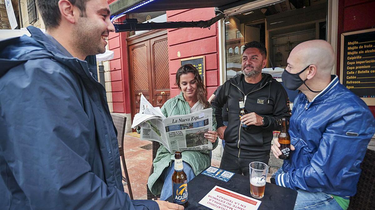 Por la derecha, Manuel Colla, Juan Carlos Álvarez, Natalia Cruz –leyendo LA NUEVA ESPAÑA– y Santi Rodríguez, ayer, en una terraza de Oviedo. | Irma Collín