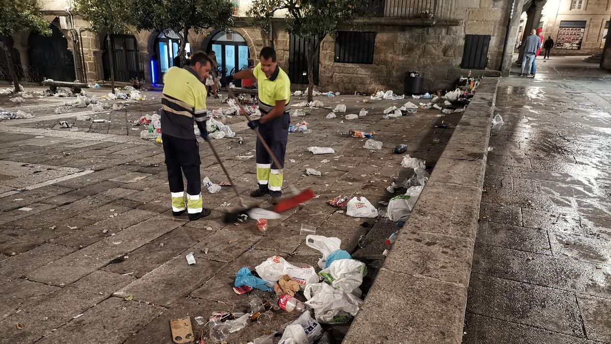Trabajadores limpian los restos de un botellón.