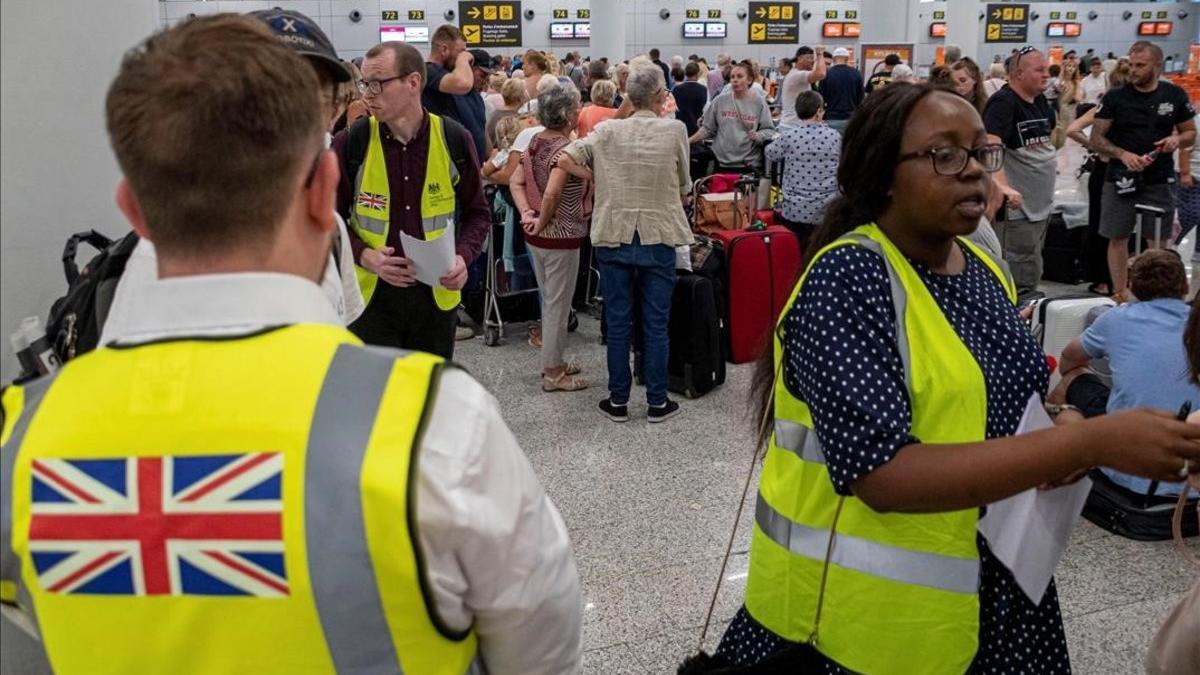 Empleados del Gobierno británico atienden, en el aeropuerto de Palma de Mallorca, a pasajeros afectados por la quiebra de Thomas Cook