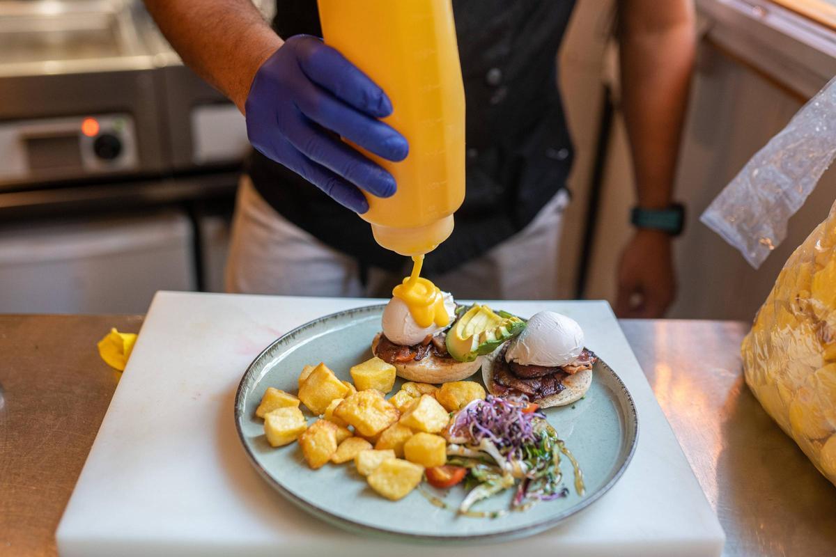 Un cocinero prepara un plato de huevos benedictinos en el restaurante Petit Pot.