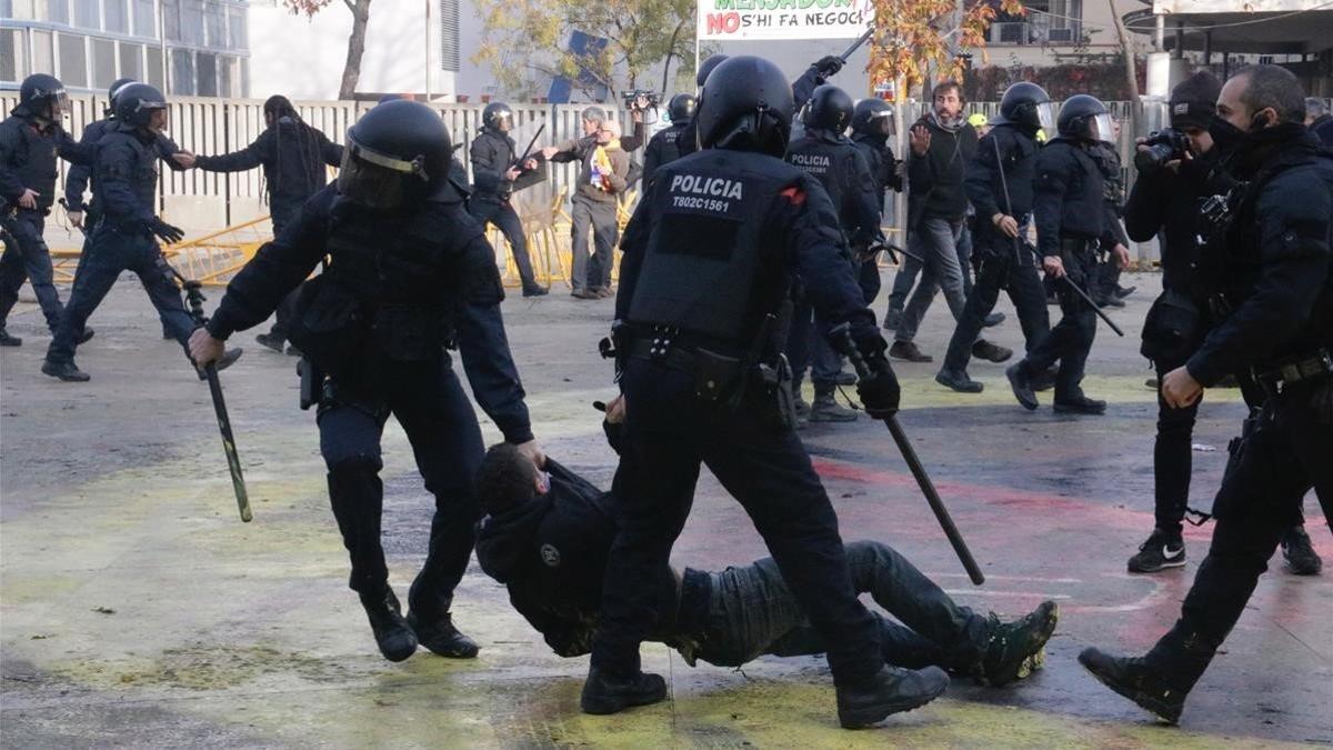 Dos mossos arrastran a un manifestante en la plaza del 1 d'Octubre de Girona