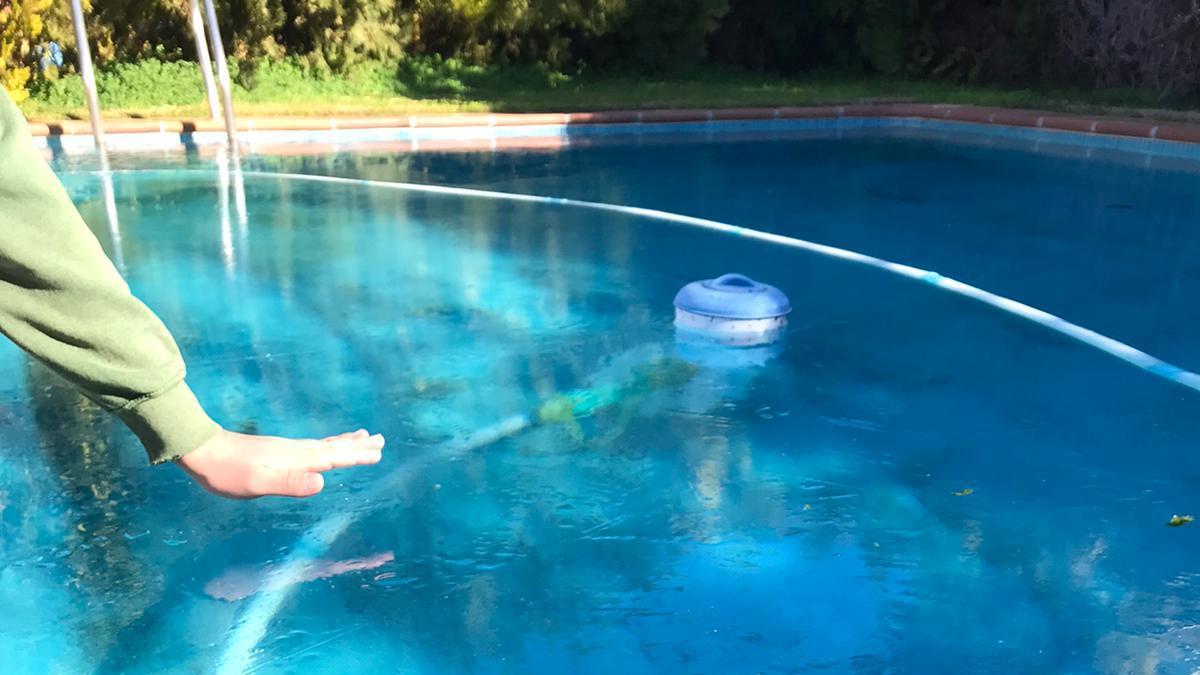 Un vecino comprueba el espesor de la capa de hielo en su piscina