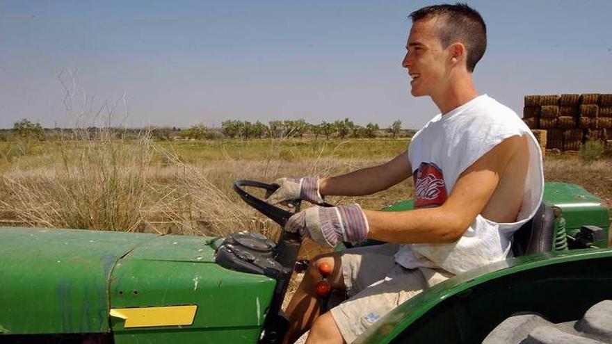 Un joven agricultor montado en su tractor.