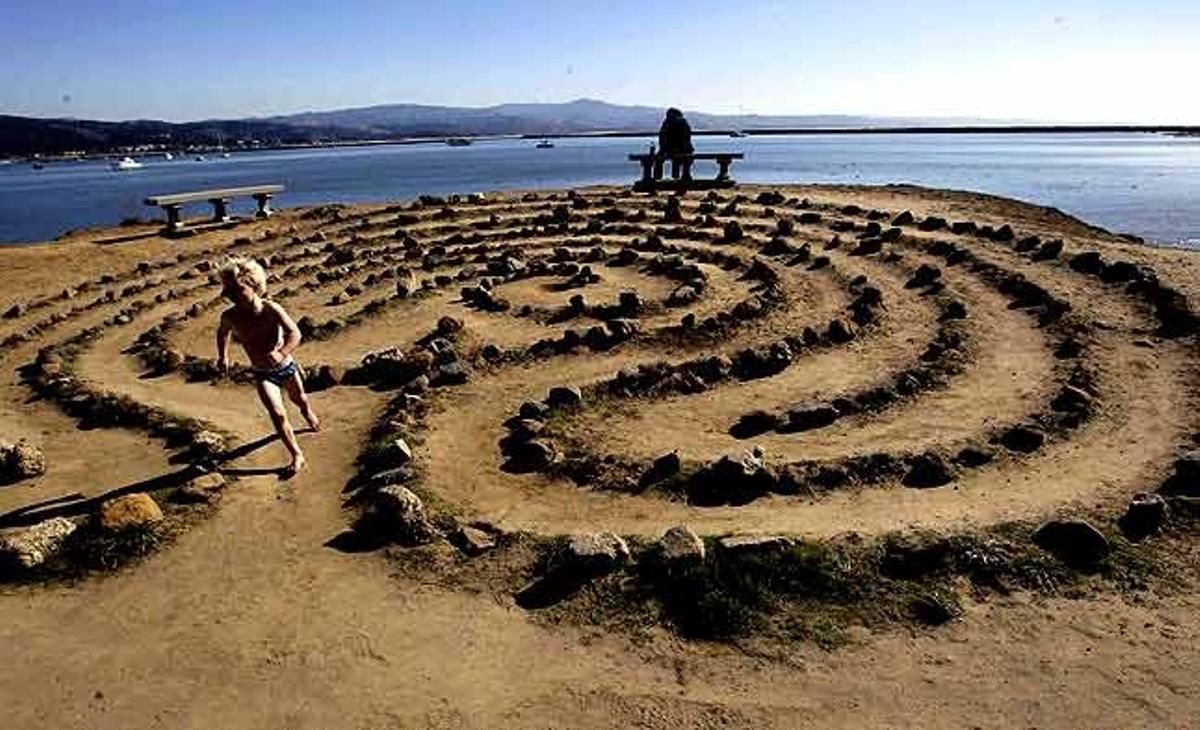 Un nen recorre un laberint improvisat a la platja en un matí assolellat a Half Moon Bay, Califòrnia (Estats Units).
