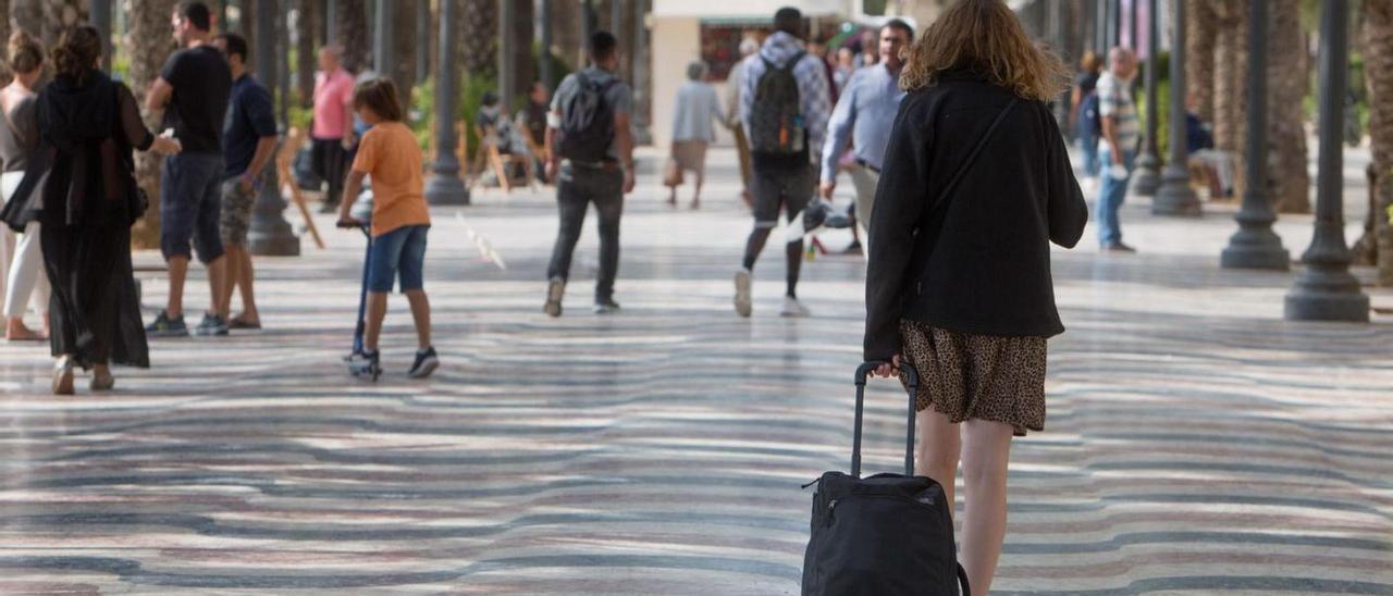 Una turista camina arrastrando su maleta por la Explanada de Alicante, ayer a mediodía. | JOSE NAVARRO