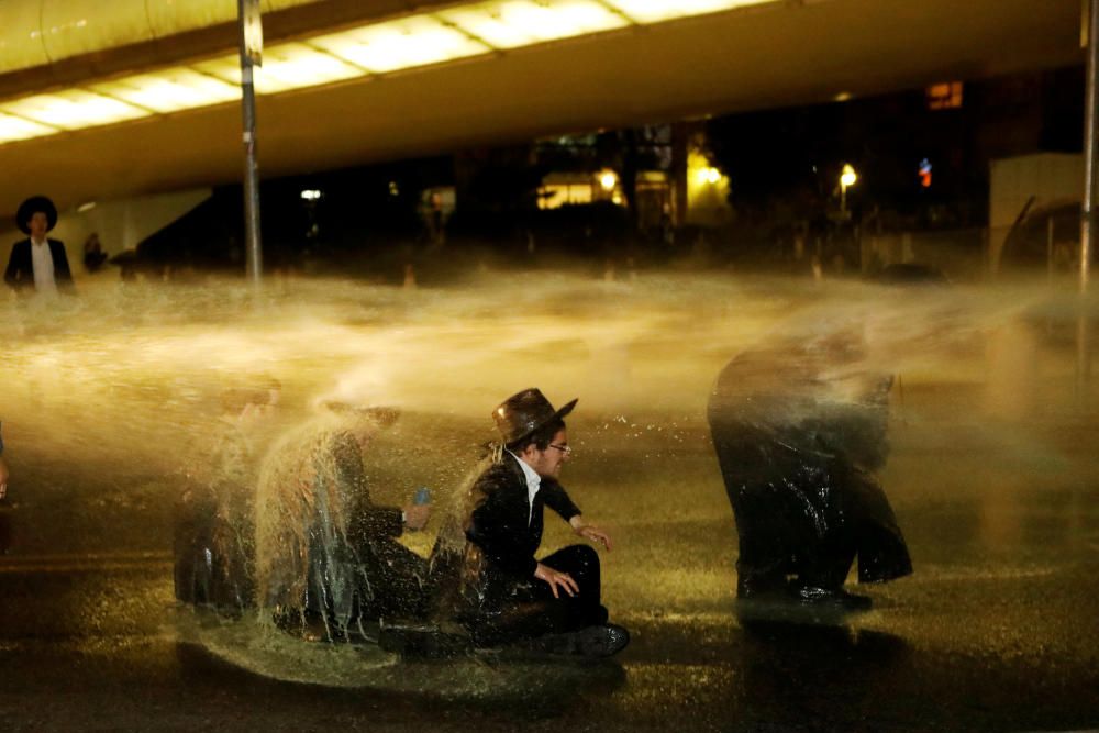 Israeli ultra-Orthodox Jewish men sit as a water ...