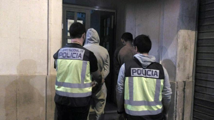 Dos agentes de la Policía Nacional custodian a dos detenidos en una operación por tráfico de drogas y robos con fuerza.