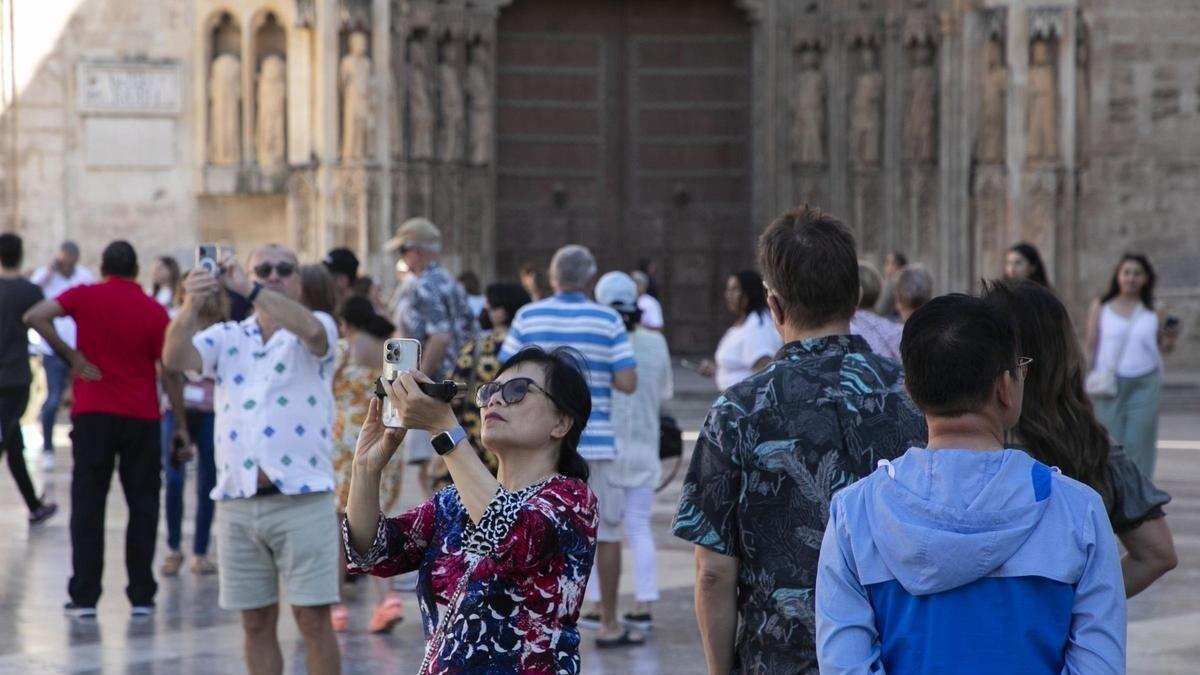 Una turista asiática toma fotos en la plaza de la Virgen de València