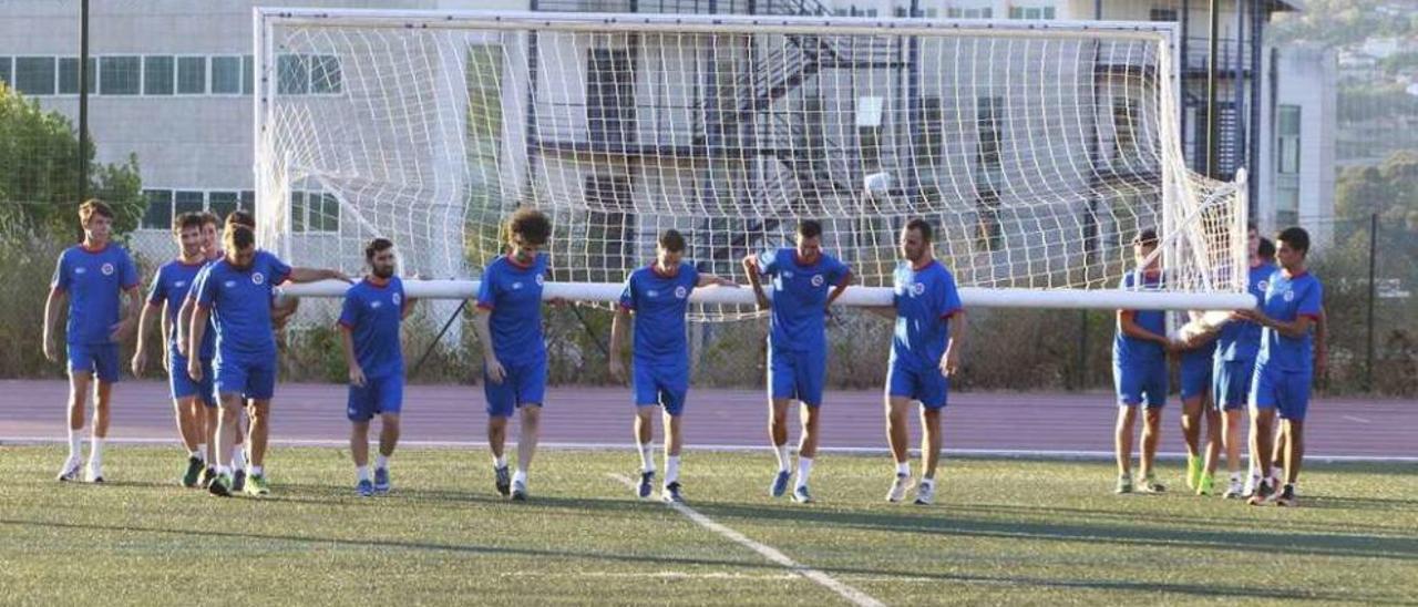 Los jugadores de la UD Ourense trasladan una portería, ayer, en el campus. // Jesús Regal