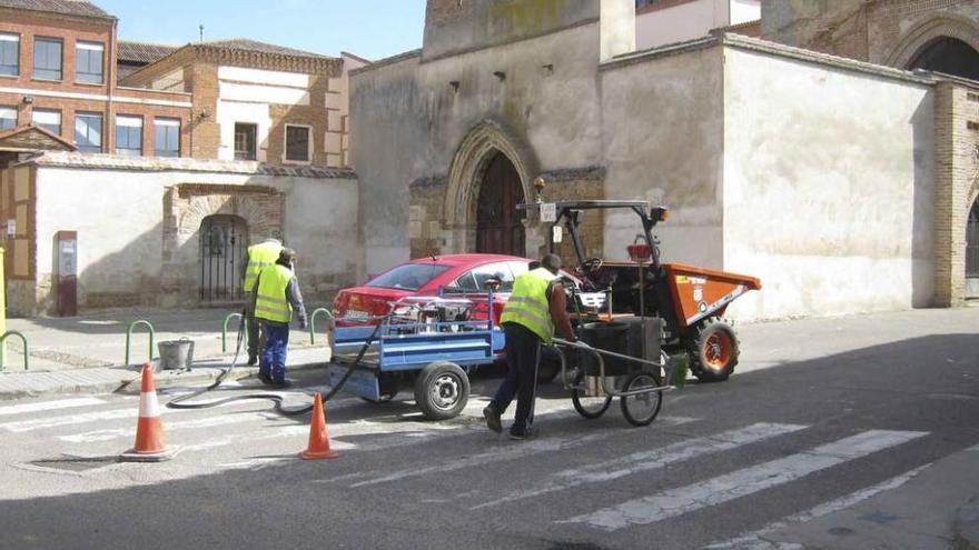 Operarios municipales taladran la acera para colocar una de las nuevas señales de tráfico. Foto