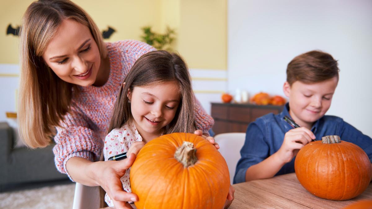 Una madre prepara con sus hijos la calabaza de Halloween.