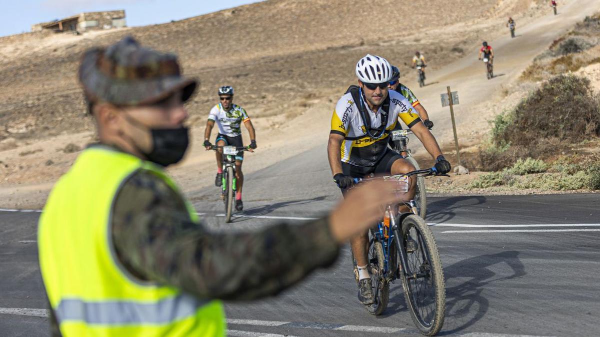 Un soldado del Regimiento de Infantería Soria 9 señala la dirección del recorrido a unos ciclistas. | | LP/DLP