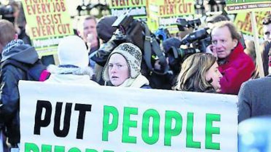 Una manifestante, ayer, en Dublín, con una pancarta que reza: «Poned a las personas antes que los beneficios. Combatid los recortes».