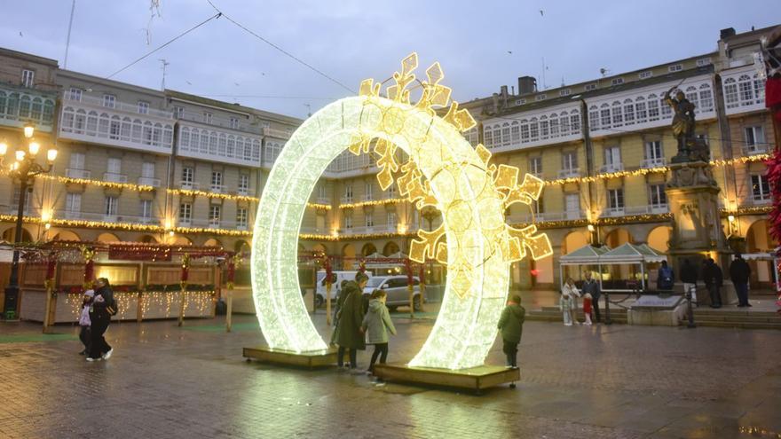 Unos niños pasan por una decoración luminosa en el poblado navideño. |  Casteleiro