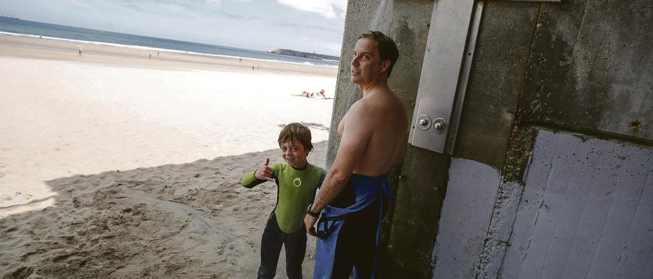 Emilio Cabezudo y su hijo Alfonso, ayer, duchándose tras salir del mar en Salinas.
