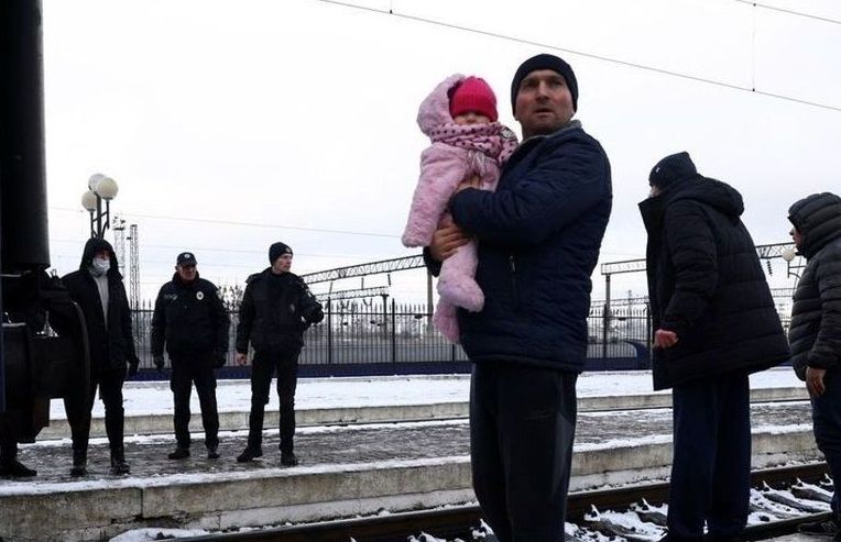 Un grupo de gente que huye de los ataques rusos en Ucrania espera para coger un tren hacia Polonia, en la estación de tren de Lviv.