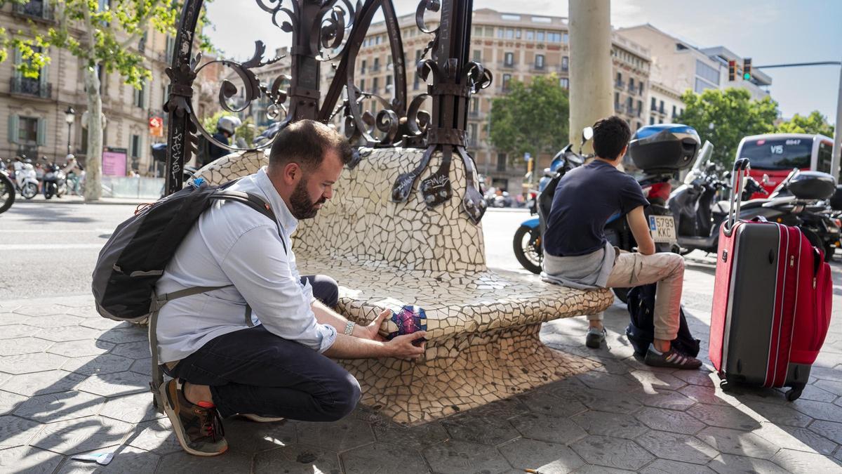 Joan Juncosa colocando uno de los parches en un banco desconchado en el paseo de Gràcia, en Barcelona.