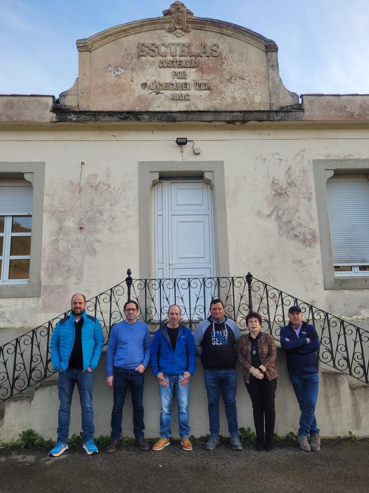 Miembros de la junta directiva de la Asociación Escueles de Muñó ante el edificio.