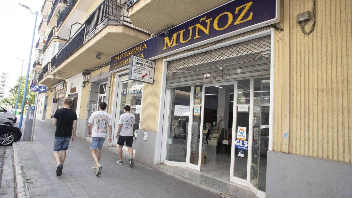 Tres jóvenes pasan por delante del local de Papelería Muñoz, ayer en Xàtiva.