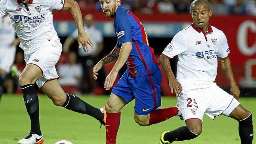 Leo Messi intenta desfer-se dels defensors del Sevilla Remi i Mariano Ferreira