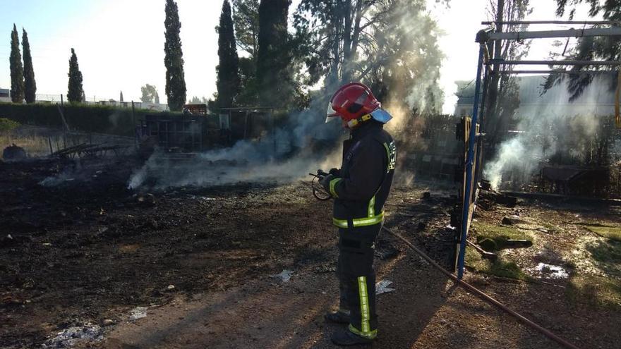 Un bombero refresca el lugar incendiado tras ser apagado el fuego.