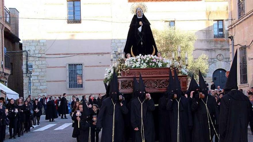 Imagen de la Virgen de la Soledad portada a hombros y acompañada por asociadas durante la procesión.