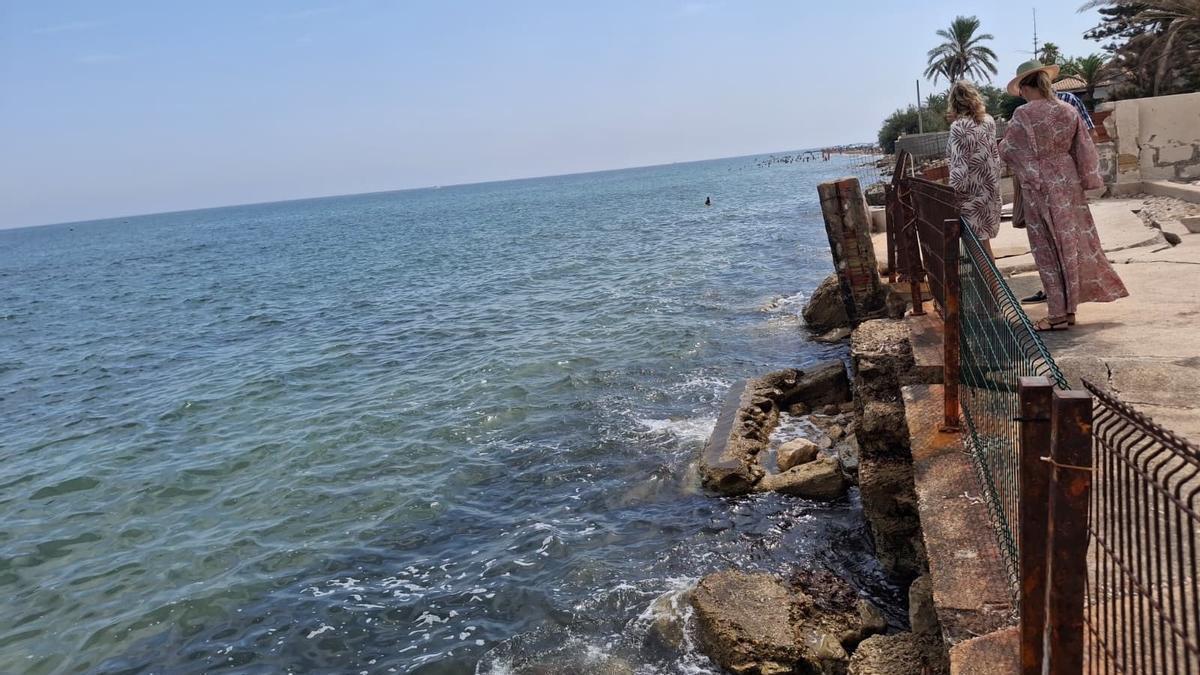 Dos vecinas se asoman al muro destrozado del chalé donde Martínez Mus se ha reunido con los afectados por los deslindes