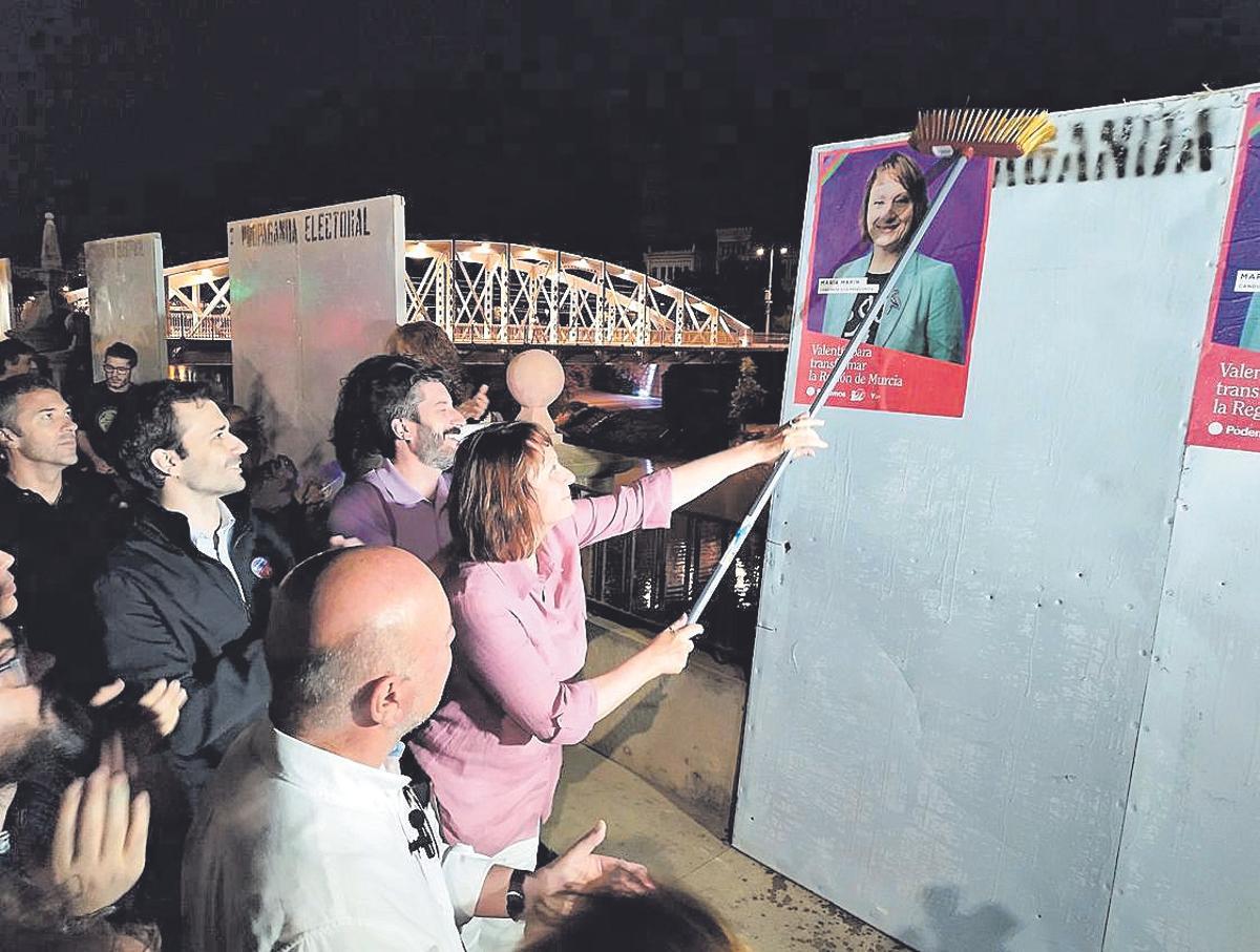 María Marín pega uno de los carteles electorales.