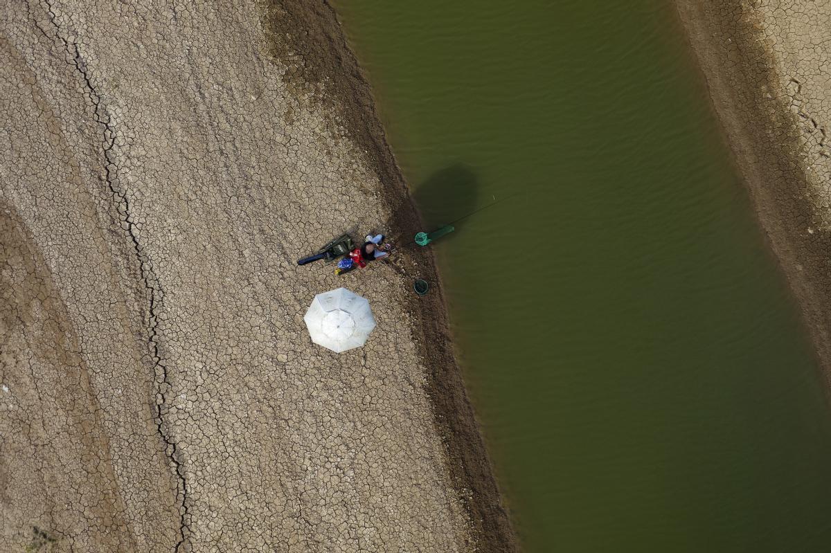 Una fotografía tomada con un dron muestra a un hombre pescando en un charco del lecho seco del río.