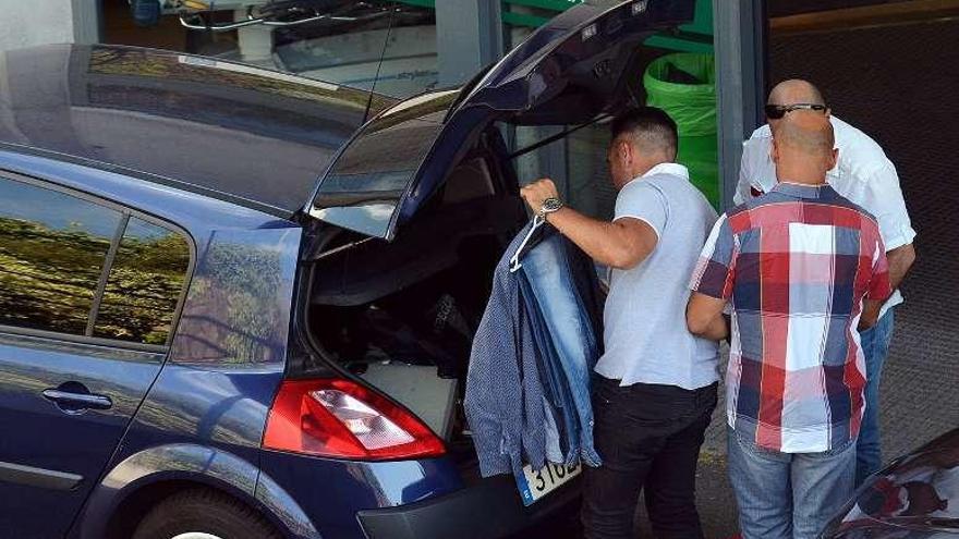 Dos policías recogen ropa para el detenido en Montecelo. // R. Vázquez