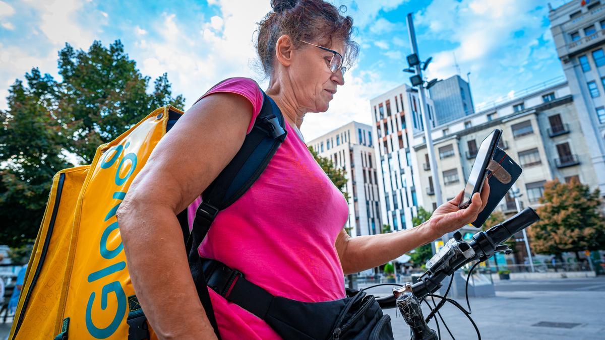 Una repartidora de Glovo mira su móvil en busca de un pedido que repartir, en la plaza España de Zaragoza.