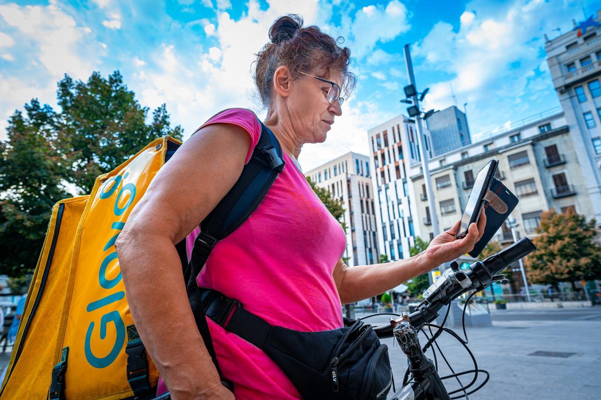 Una repartidora de Glovo mira su móvil en busca de un pedido que repartir, en la plaza España de Zaragoza.