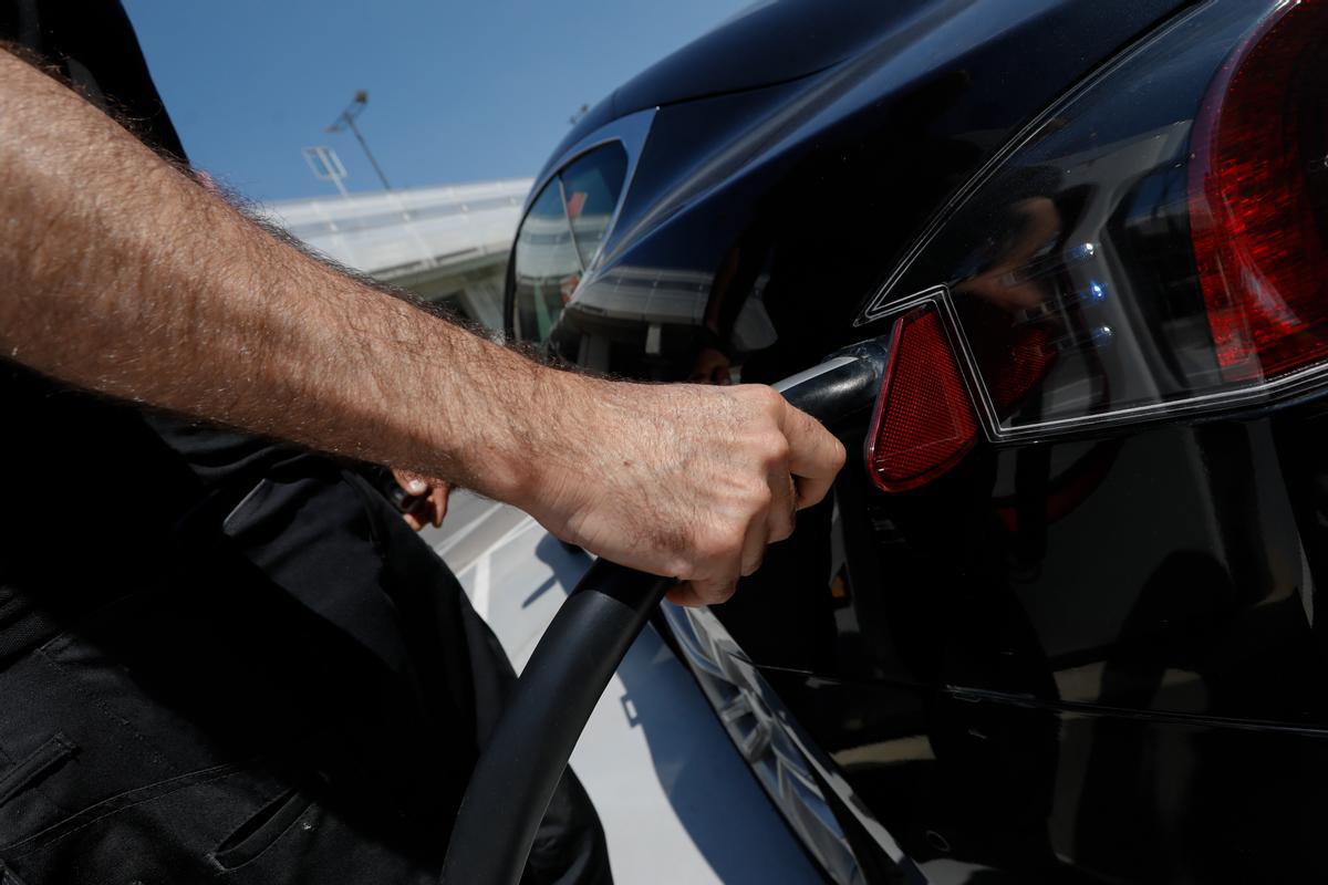 Persona recarga un coche eléctrico en un punto de recarga.