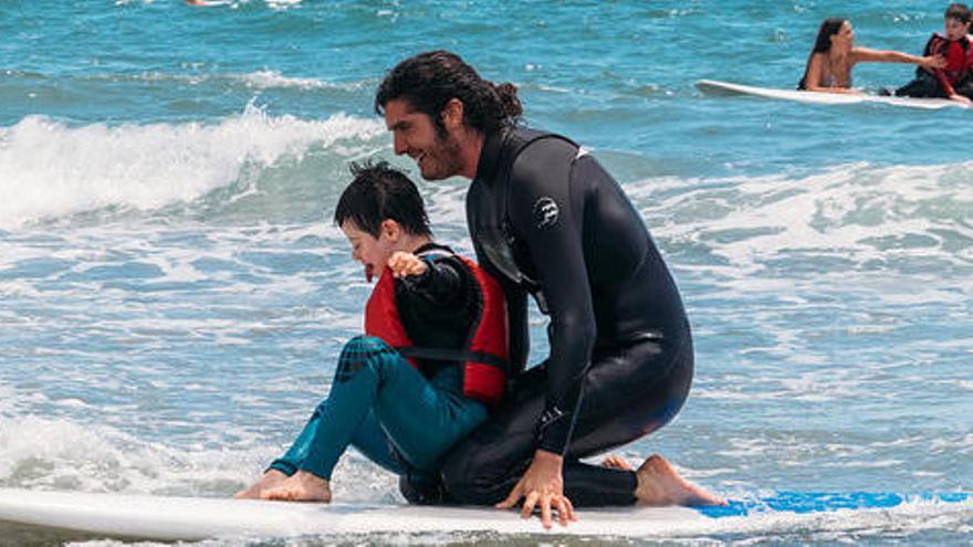 Un monitor fent teràpia de surf amb un nen a Sitges