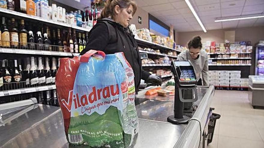 Una clienta compra un paquet d&#039;aigua embotellada al supermercat Bonarea de Calaf