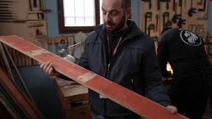 Un preso sostiene un trozo de madera procedente de una barca en la que viajaban inmigrantes llegados a Lampedusa, parte del proyecto Violines del mar