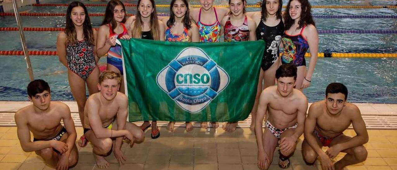 Los nadadores del Santa Olaya que representarán al club en el Nacional infantil posan con su bandera en las instalaciones olayistas.