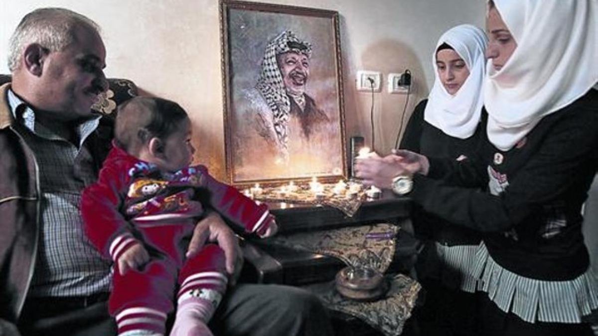 Una familia palestina enciende velas junto a un retrato de Yaser Arafat, el pasado 2 de noviembre, en Hebrón.