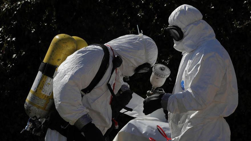 Dos trabajadores se preparan para desinfectar una ambulancia.