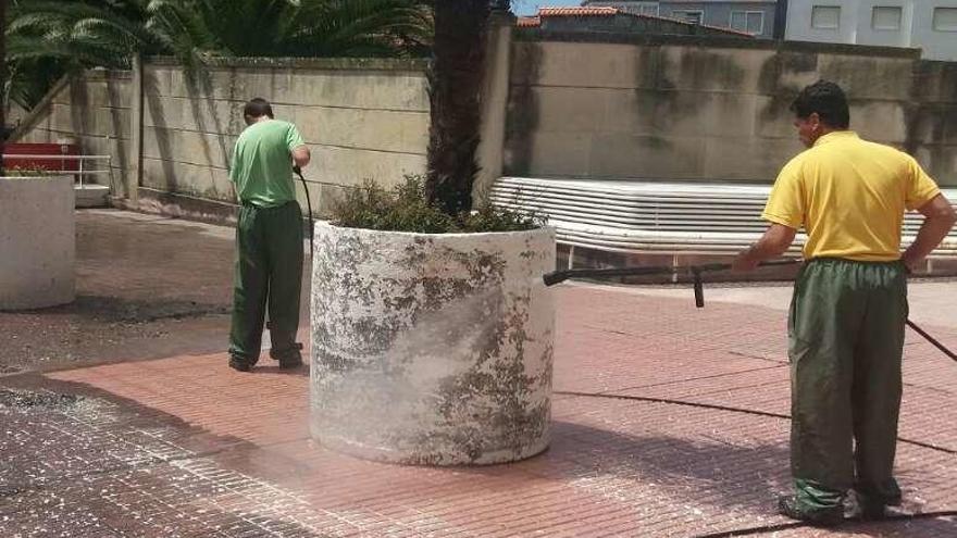 Dos operarios durante las labores de limpieza en la Praza do Pazo.