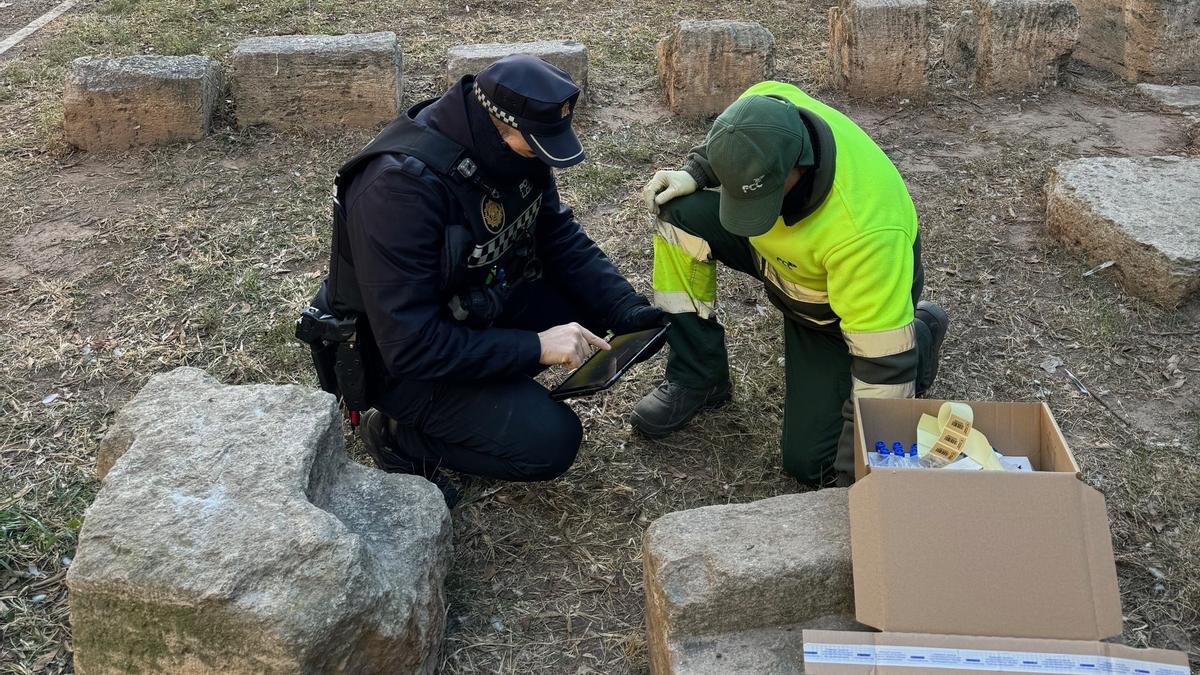 Un agente de policía local y un trabajador de mantenimiento y limpieza recogen muestrar para analizar