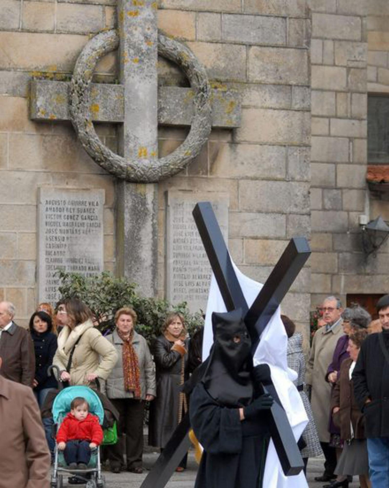 Una procesión pasa ante la cruz falangista de Santa Eulalia. 