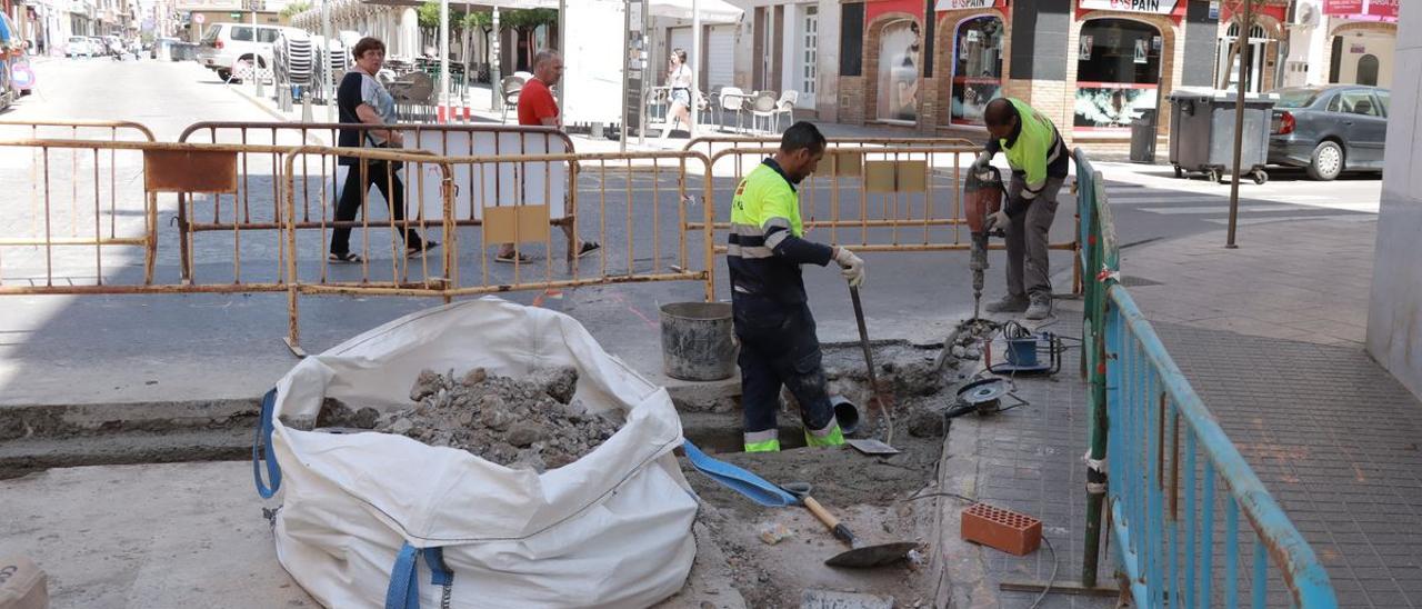 Dos operarios trabajan en una conexión para desviar parte de las agua pluviales que bajan por la calle Sant Joaquim.