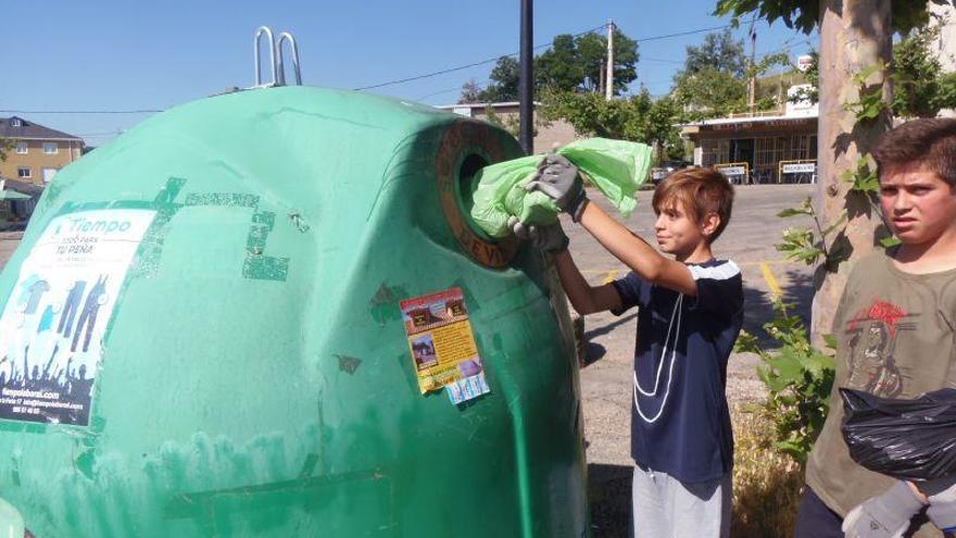 Un alumno del CEIP Monte Gándara deposita la basura recogida en un contenedor de reciclaje.