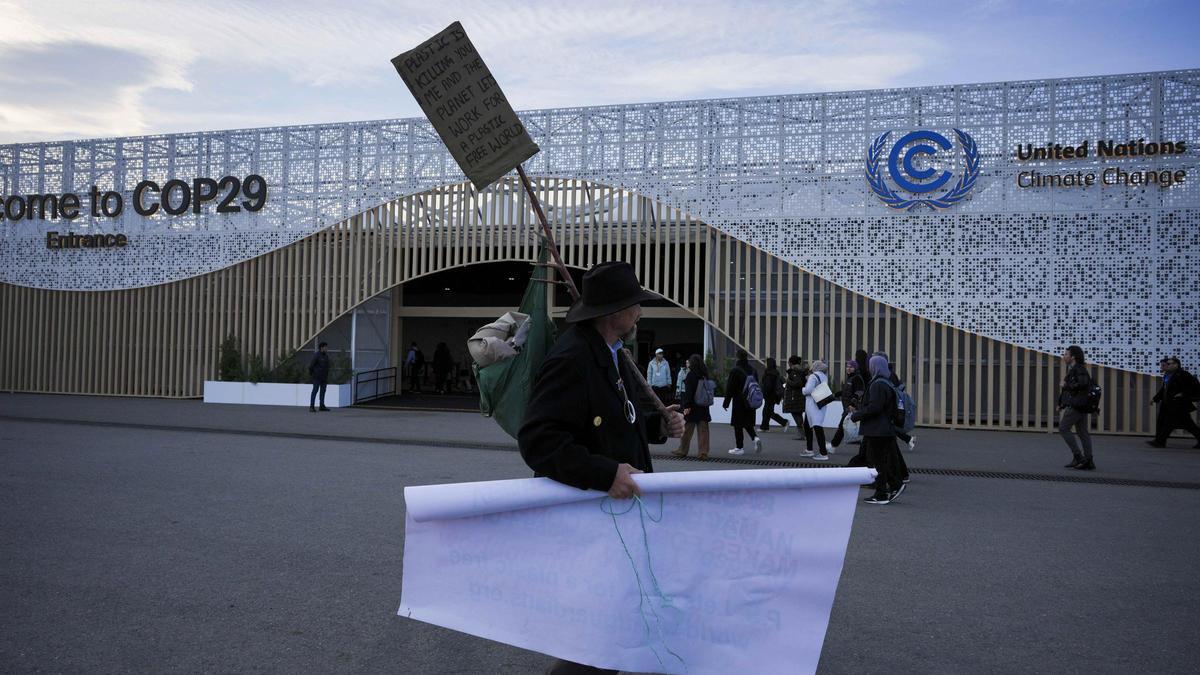 Un hombre protesta contra la contaminación de los plásticos junto al edificio de Bakú que alberga la cumbre del clima COP-29.