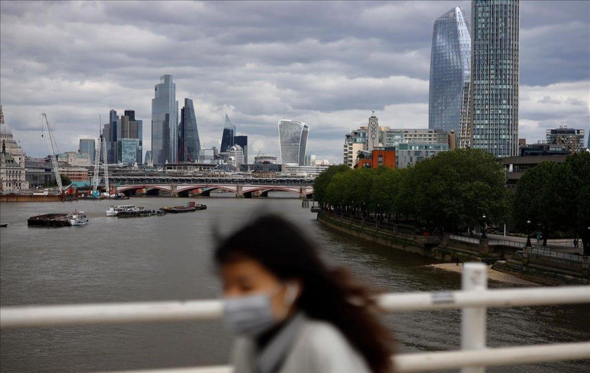 Una peaton cruza el puente de Waterloo, sobre el Támesis, con la City al fondo.